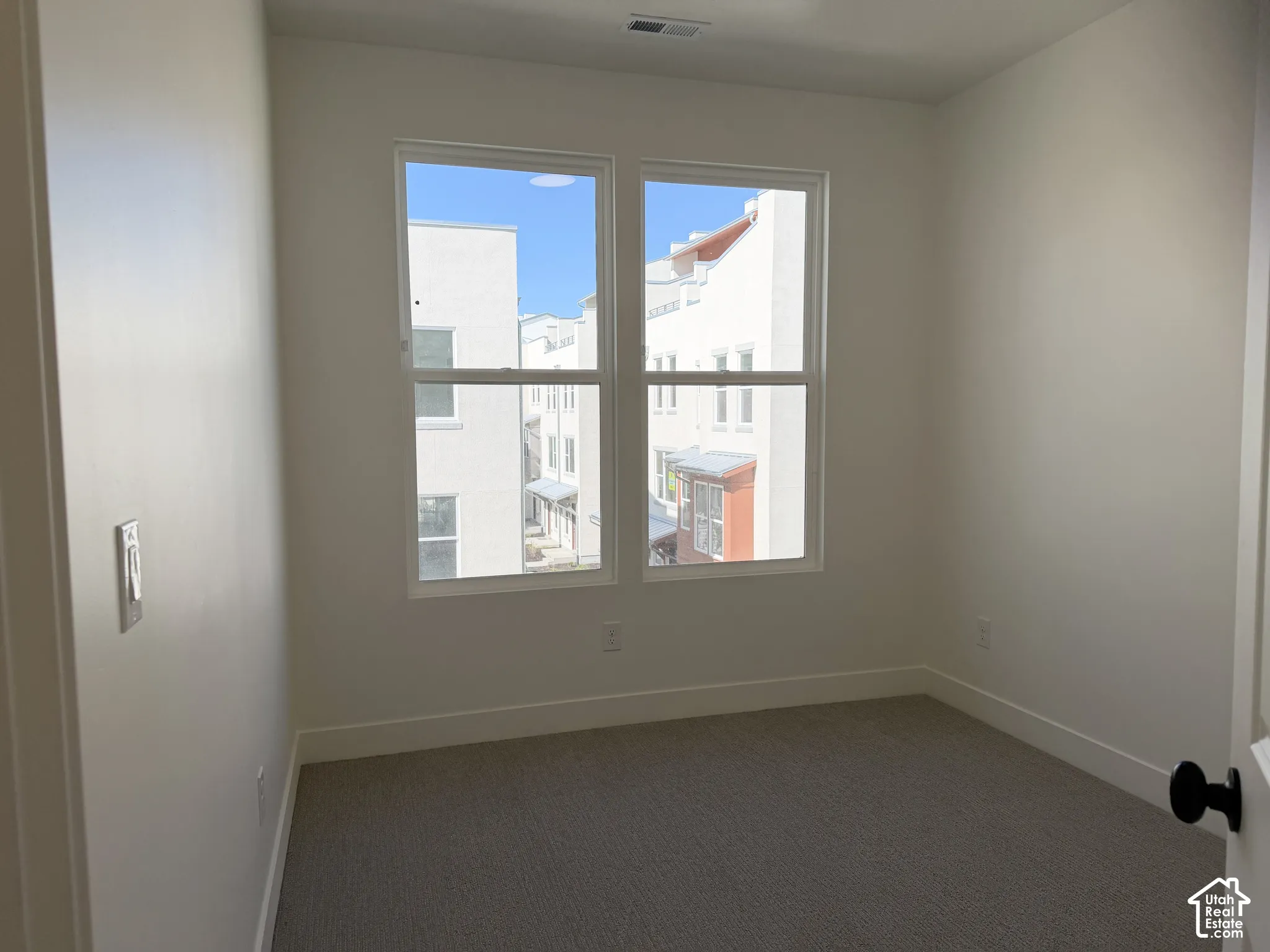 Neutral wall paint, dual pane windows, carpeting, white trim, and a contemporary black door handle