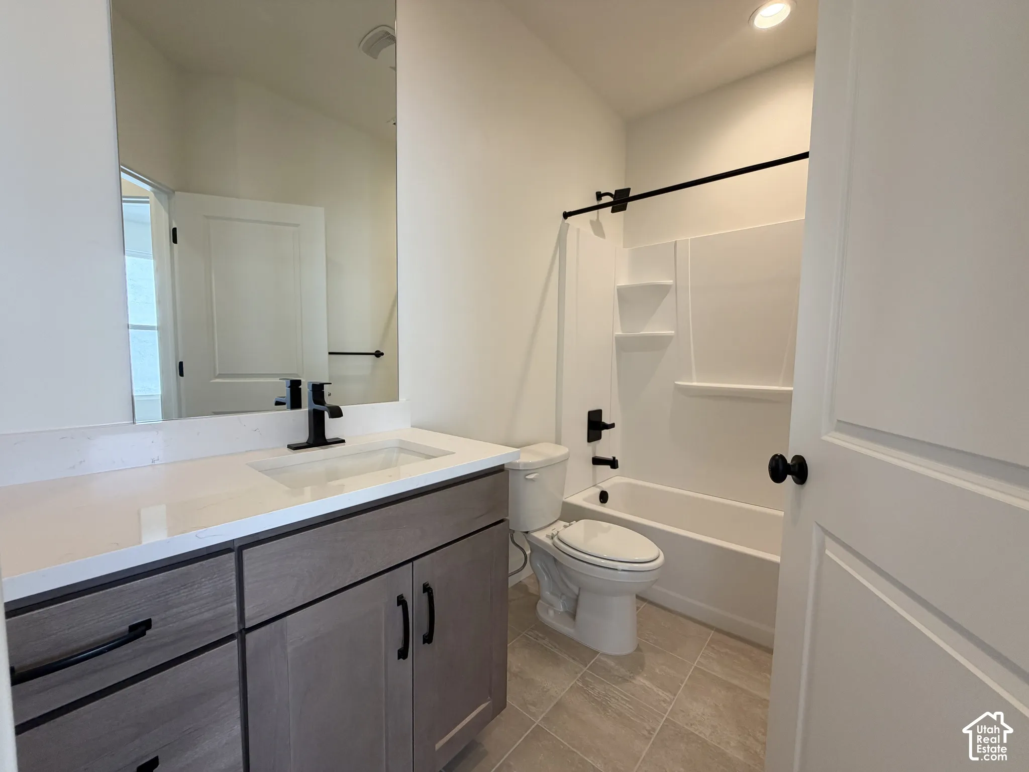 Bathroom featuring a wood-finish vanity with black hardware, white countertop with an integrated sink, and a black-finish faucet