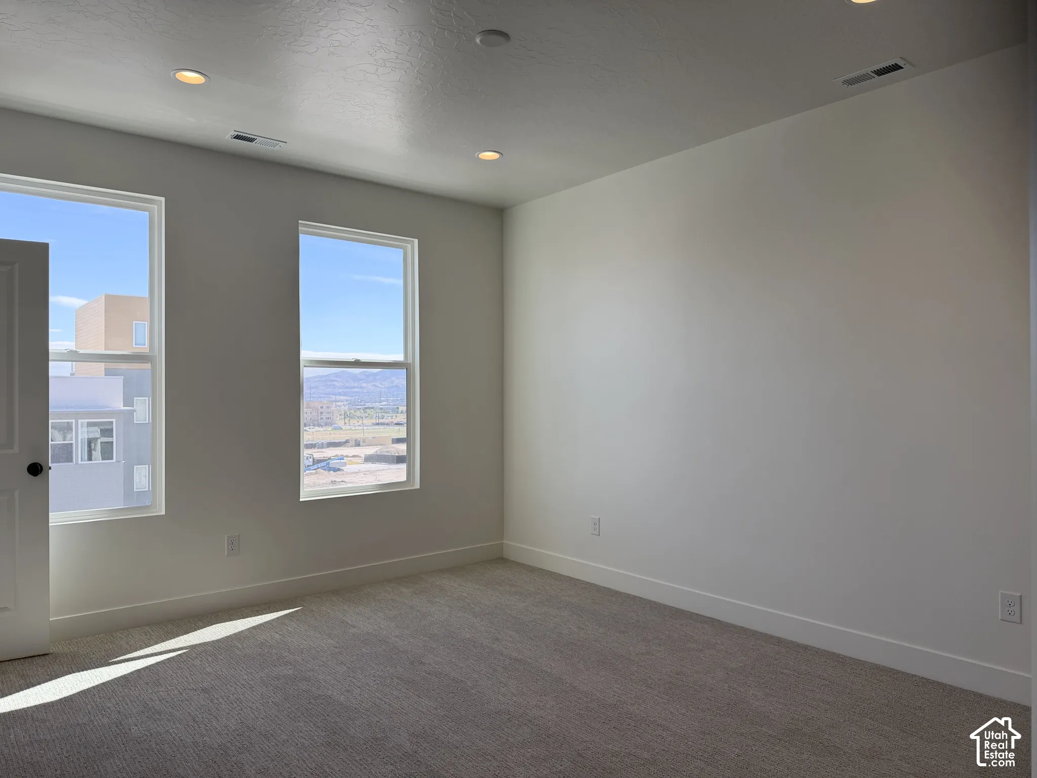 Wall-to-wall carpeting, white interior walls, two large windows, white trim, and recessed ceiling lighting