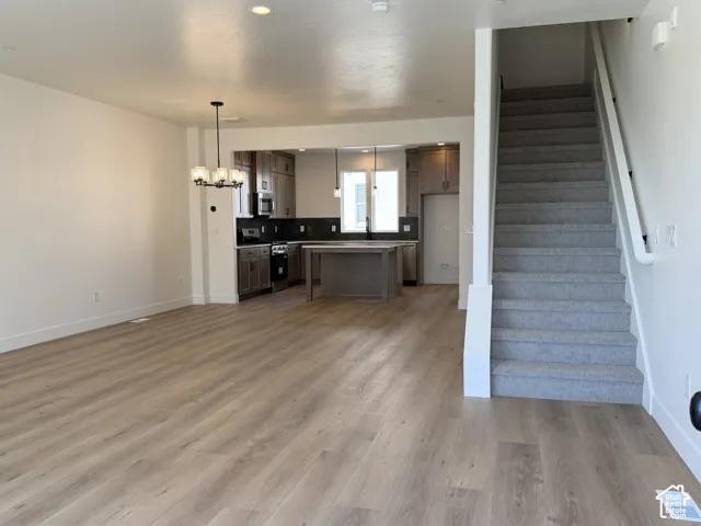 Open-concept living area featuring wood-finish flooring, recessed lighting, and a modern chandelier