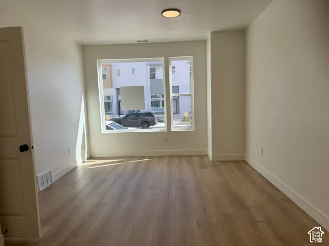 Wood-finish flooring, white trim, recessed lighting, and a double-pane window