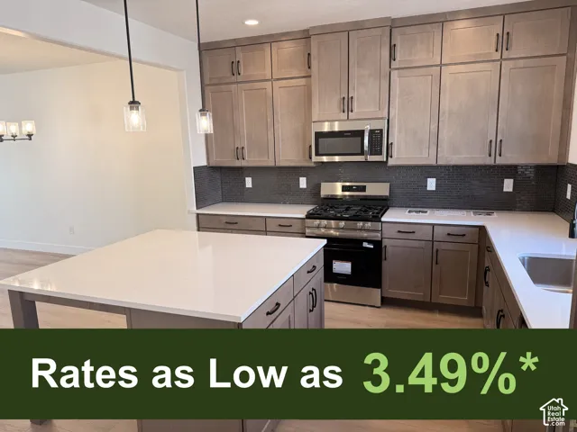 Kitchen featuring a large island, stainless steel appliances, light wood-finish cabinetry, white countertops, and a dark tile backsplash