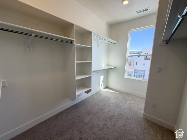 Walk-in closet with built-in shelving, hanging rods, and a window for natural light
