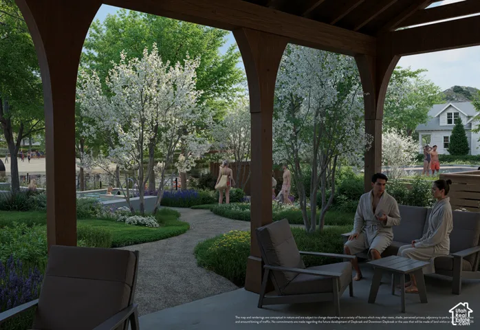 Covered patio featuring arched wood-grain support beams and concrete flooring, overlooking a landscaped garden with gravel pathways, flowering trees, and integrated water features