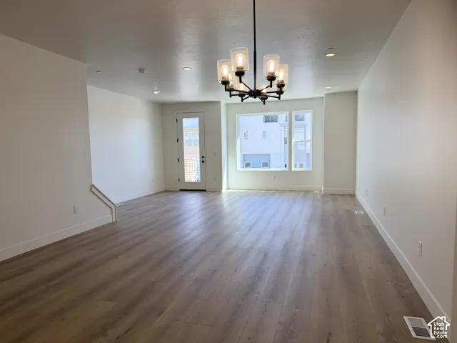 Spacious living area featuring wood-finish flooring, a modern chandelier, recessed lighting, and large windows