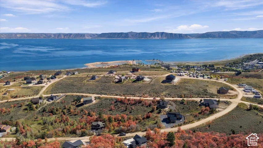 Expansive lakefront property featuring a clear blue lake, distant mountainous terrain, and surrounding residential developments
