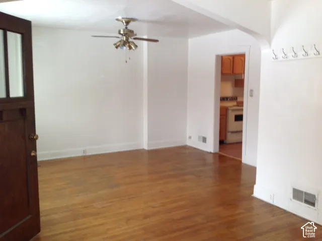 Wood-finish flooring, ceiling fan with light kit, kitchen pass-through, and wall-mounted coat hooks