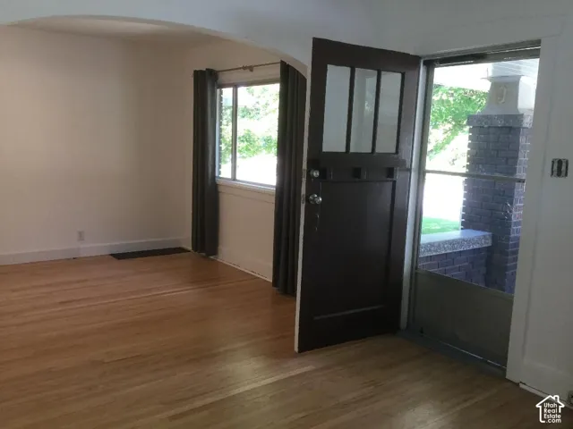 Hardwood flooring throughout, arched doorway, multi-pane entry door, and a brick exterior element