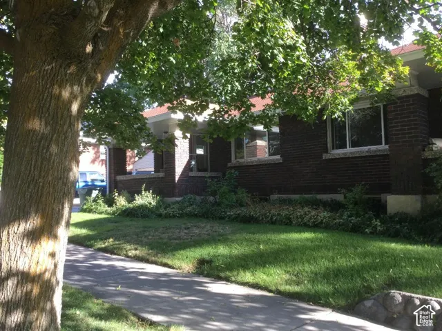 Brick exterior with white window frames, covered porch, and mature landscaping