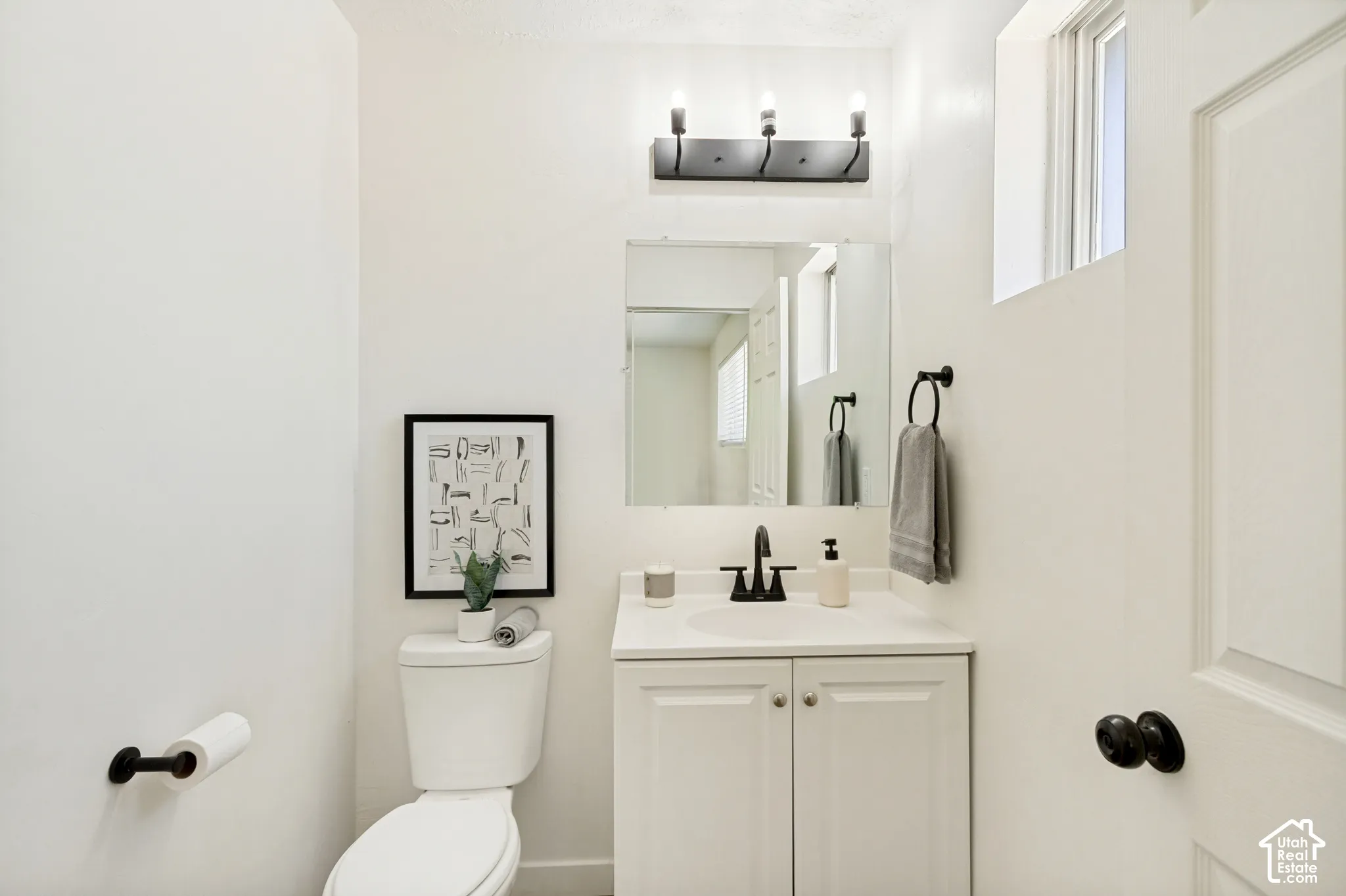White vanity with cabinet storage, matte black faucet, and coordinating mirror