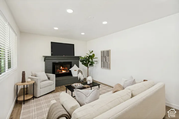 Recessed lighting, wood-finish flooring, and a fireplace with a dark-toned surround