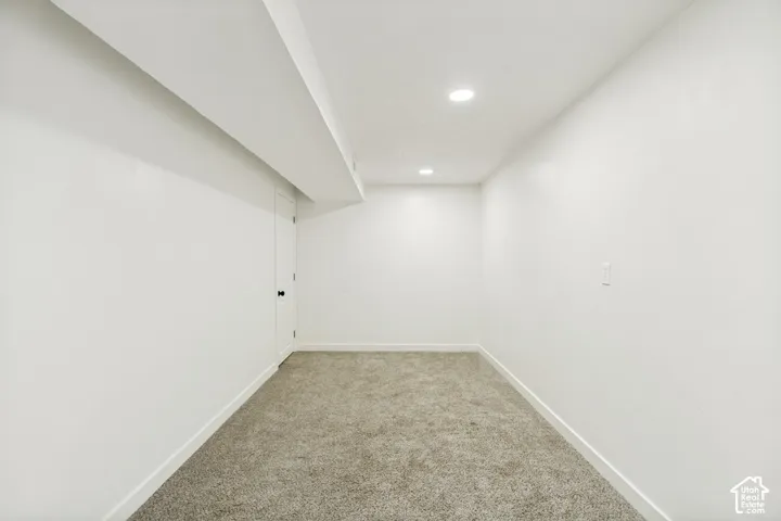 Recessed lighting fixtures illuminate this room with white walls and light-toned carpeting