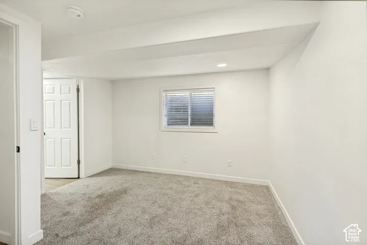 Recessed lighting, light gray carpeting, white walls, and a multi-pane window with blinds