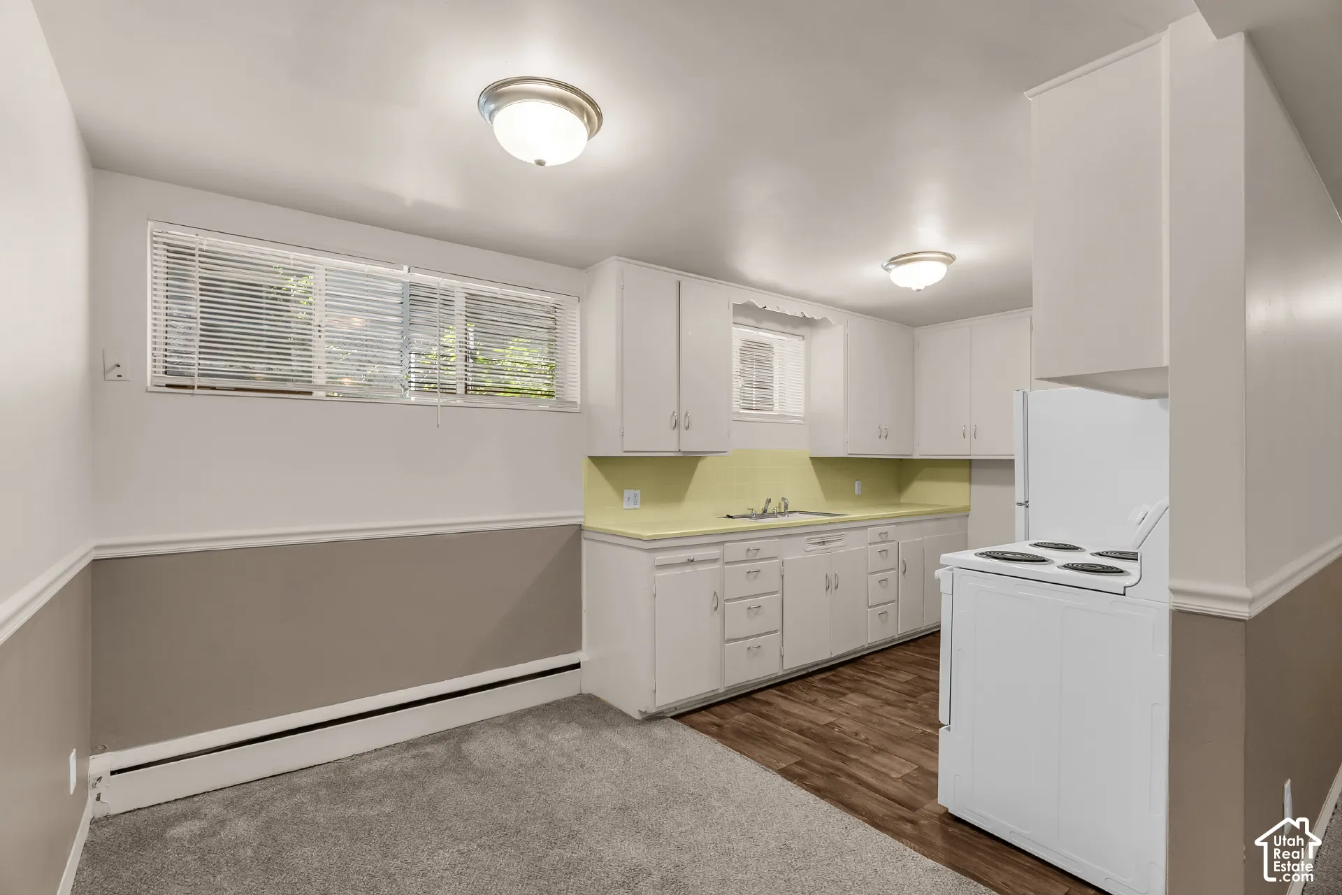 White cabinetry with integrated sink, wood-finish flooring, and wall-mounted light fixtures