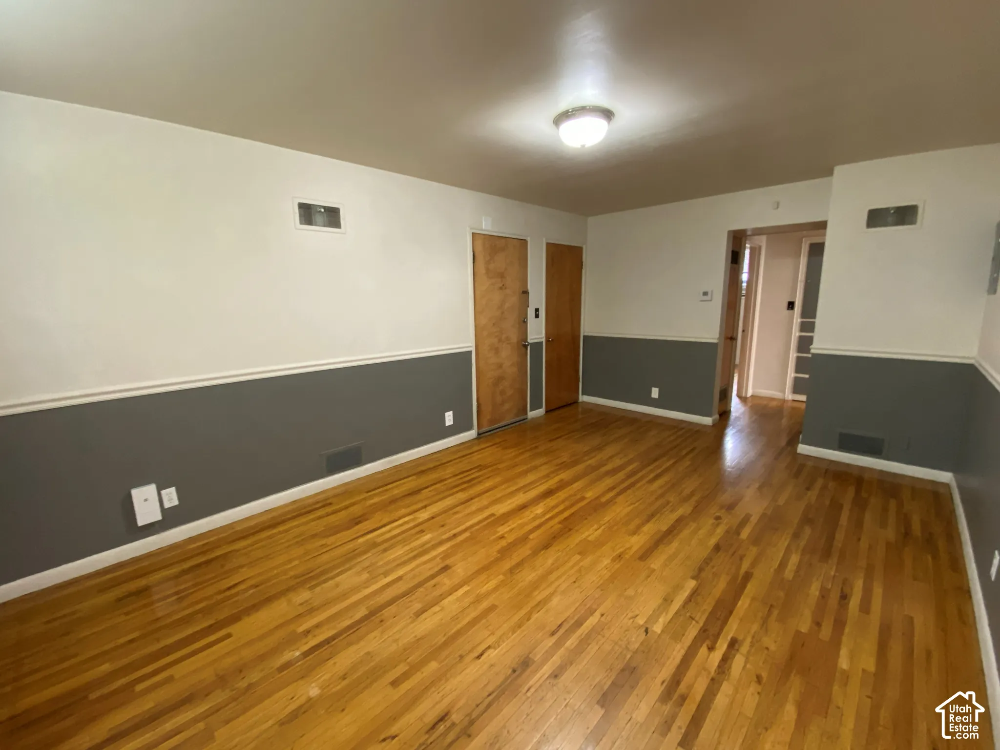 Hardwood-finish flooring, two-tone wall paint, crown molding accent, and wood doors