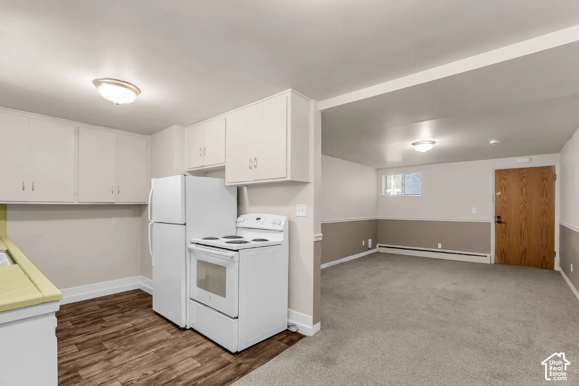 Kitchen featuring wood-finish flooring, white cabinetry, and white appliances