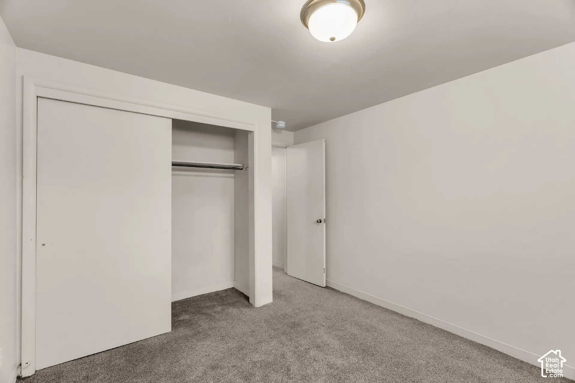 Recessed closet with sliding doors, neutral wall paint, and overhead flush-mount lighting