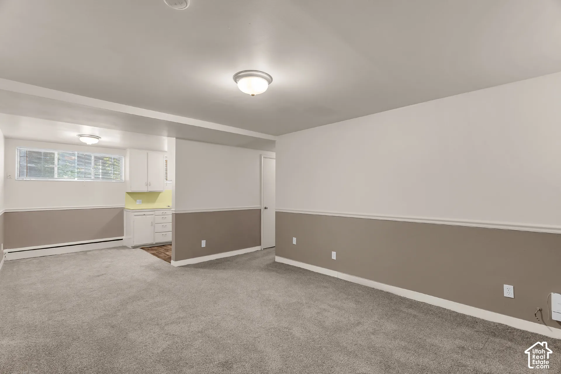 Carpeted flooring throughout, two-tone wall paint, built-in cabinetry, and window with blinds