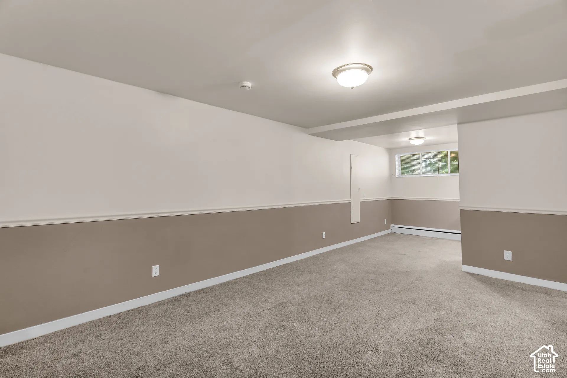 Spacious room featuring neutral carpeting, two-tone wall paint, and multiple windows
