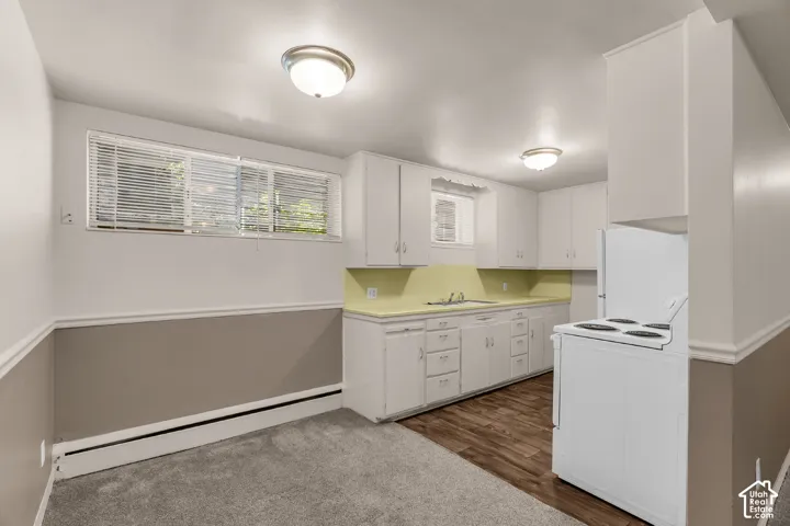 White cabinetry with integrated sink, wood-finish flooring, and wall-mounted light fixtures