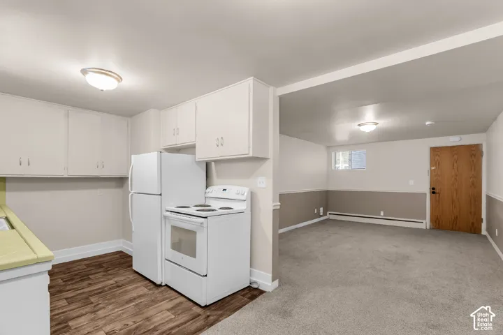 Kitchen featuring wood-finish flooring, white cabinetry, and white appliances