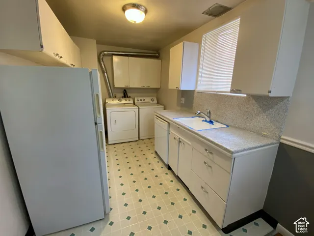 White cabinetry, patterned flooring, light-colored countertops, and a window with blinds