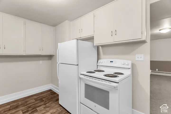 Kitchen featuring wood-finish flooring, white cabinetry, a white refrigerator, and a white electric range