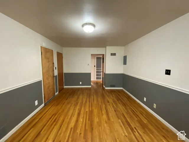 Hardwood flooring, two-tone painted walls with chair rail molding, ceiling-mounted light fixture, and two wood-finish doors