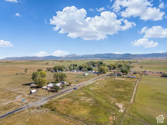 Expansive rural landscape featuring a paved road, scattered structures, and distant mountains