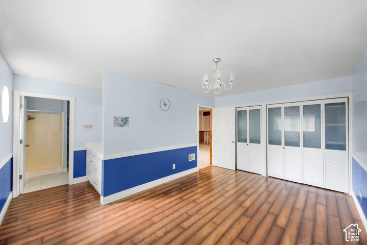 Wood-finish flooring, built-in storage with countertop, white bifold closet doors with frosted panels, interior door access, and a ceiling-mounted chandelier