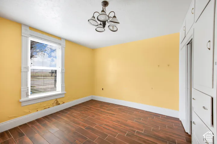 Wood-finish flooring, built-in cabinetry, an ornate ceiling light fixture, and a window with detailed trim