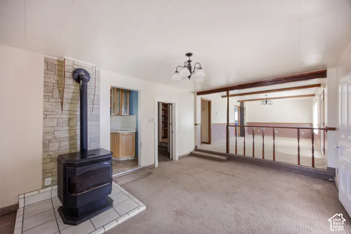 Wood-burning stove set on a tiled hearth, stone-finish accent wall, and a wood railing separating two floor levels
