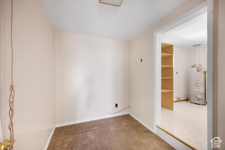 Built-in shelving, water heater, carpeted flooring, and light-colored walls