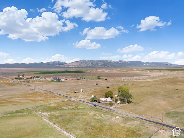 Expansive rural landscape featuring a paved road and distant mountainous terrain
