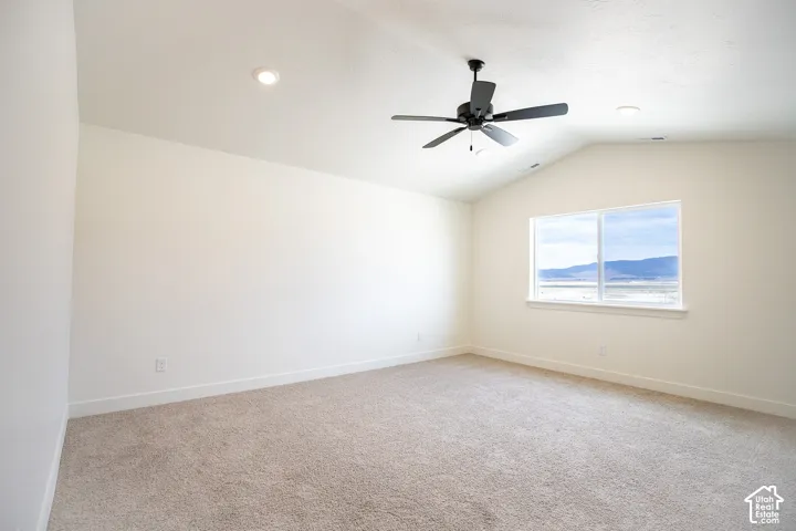 Primary bedroom with vaulted ceiling and ceiling fan.