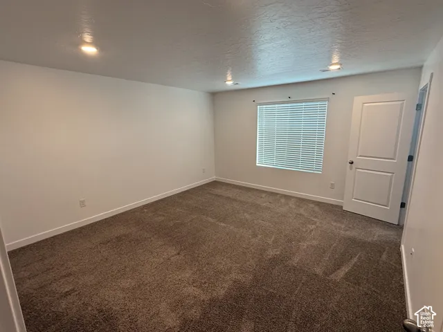 Carpeted room featuring a white paneled door, recessed lighting, and a window with blinds