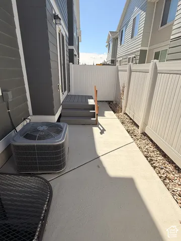 Private outdoor patio featuring a composite deck, concrete pathway, and vinyl fencing