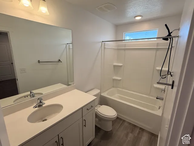 Bathroom with a single vanity, a large wall mirror, a built-in tub and shower, and wood-finish flooring