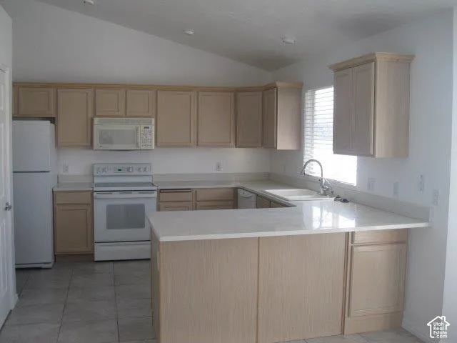 Kitchen featuring a vaulted ceiling, wood-finish cabinetry, light-toned countertops, white appliances, and tile flooring