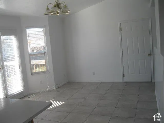 Vaulted ceilings, tiled flooring, white panel door, white window blinds, and a built-in chandelier