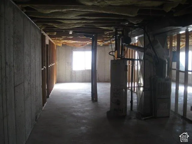 Unfinished basement with concrete flooring, exposed ceiling joists, and a single window