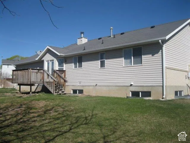 Expansive rear exterior featuring a wooden deck with railing and stairs, light-toned siding, and a gray shingle roof