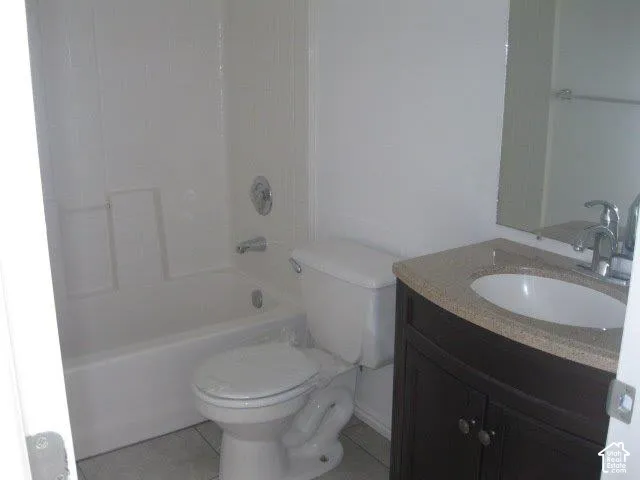 Full bathroom featuring a white tub, shower with white tiled surround, toilet, vanity with dark wood-finish cabinetry, and a light-toned countertop with integrated sink