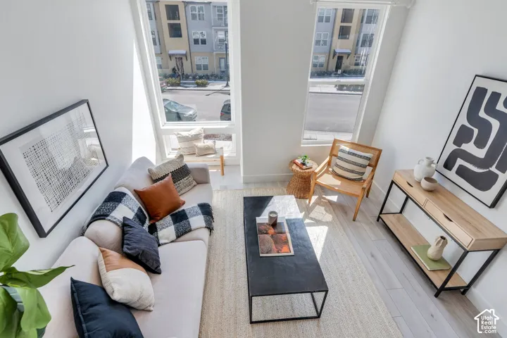 Two-story windows, light wood-finish flooring, white wall finishes, and a linear console table
