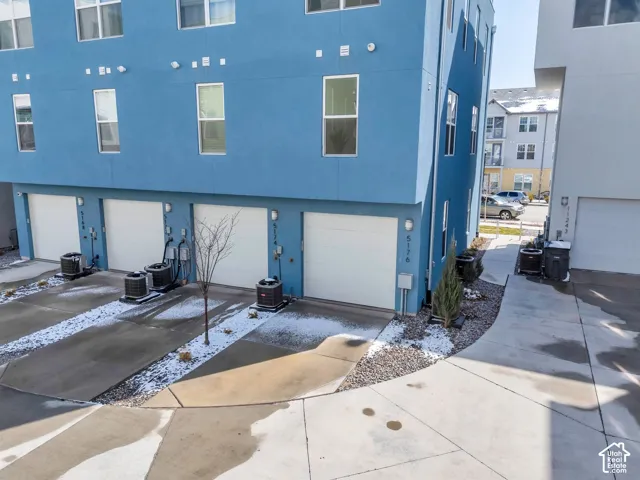Multi-level stucco exterior with multiple windows, individual garage doors, and individual exterior units