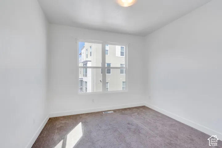 Neutral white wall paint, light-colored carpet flooring, and a multi-pane window