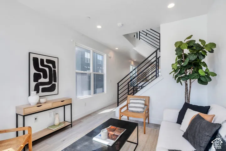 Recessed lighting, wood-finish flooring, staircase with metal railings, large window, clean white wall finishes