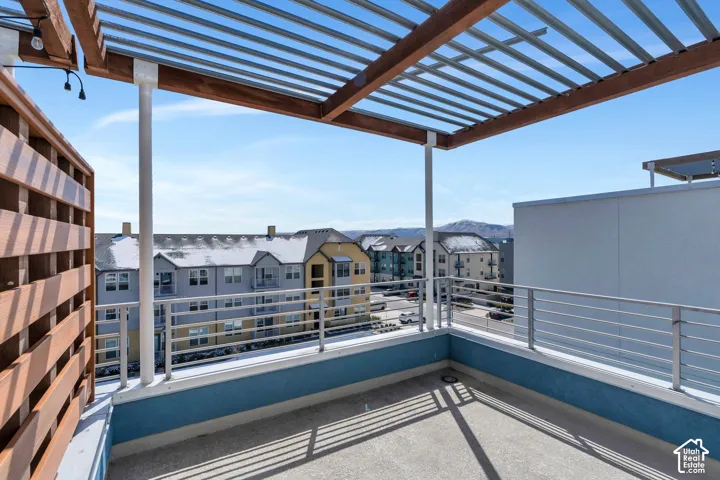 Rooftop patio featuring a slatted pergola, metal railings, and a privacy screen