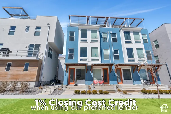 Contemporary multi-level townhome with a blue and white facade, featuring large windows, a flat roofline, and an integrated rooftop pergola