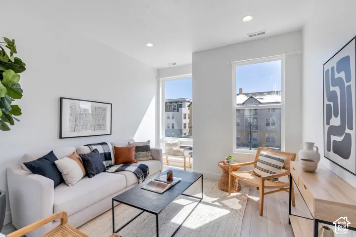 Recessed lighting, light wood-finish flooring, and multiple windows create a bright living space